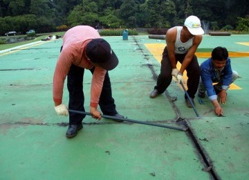 Dua pekerja mencongkel lempengan baja di landasan helikopter atau helipad. (ilustrasi)