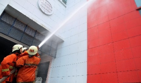 Dua pemadam kebakaran melakukan simulasi pemadaman kebakaran di sebuah gedung bertingkat di Jakarta.