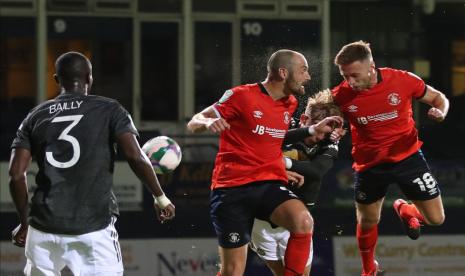 Dua pemain Luton Town (baju merah) berebut bola dengan pemain Manchester United pada pertandingan Piala Liga Inggris.