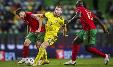 Dua pemain Portugal Danilo Pereira (kanan) dan Diogo Jota (kiri) mengapit pemain Swedia Dejan Kusulevski saat kedua tim bentrok di Lisbon, dalam lanjutan Liga Bangsa-Bangsa, Kamis (15/10).