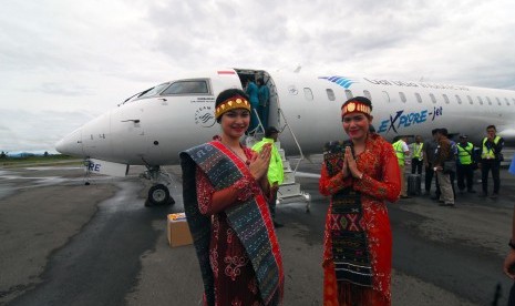 Dua perempuan berbusana daerah khas Tapanuli menyambut kedatangan pesawat CRJ 1000 milik maskapai Garuda Indonesia yang melakukan penerbangan perdana dari Jakarta ke Silangit, Tapanuli Utara, Sumatera Utara, Selasa (22/3). 