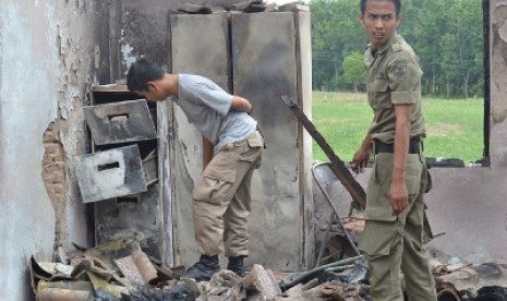  Dua personel Satpol di bekas perkantoran Pemkab Mesuji, mengais puing-puing kebakaran untuk mencari barang yang masih diselamatkan, Jumat (4/5). 