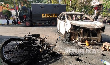 Dua personil Brimob berada di dekat kendaraan yang terbakar di Jayapura, Papua, Jumat (30/8/2019). 