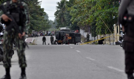 Dua personil polisi bersenjata lengkap berjaga-jaga di jalan raya tepat didepan markas Polsek Kota untuk menghalau warga sipil menuju tempat kejadian perkara (TKP) adanya benda diduga berisi bom, di Poso, Sulawesi Tengah, Rabu (11/3). 