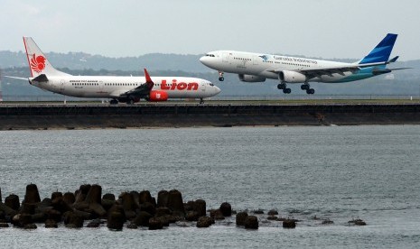 Dua pesawat terbang dan mendarat di landasan pacu Bandara Ngurah Rai, Bali, Senin (19/6). 