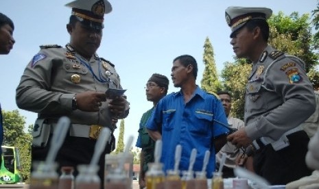 Dua petugas kepolisian memeriksa hasil tes urine dan kesehatan para sopir bus (ilustrasi).  