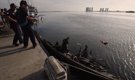 Dua petugas Komite Nasional Keselamatan Transportasi (KNKT) mengamati Kapal Zahro Express yang terbakar saat melakukan investigasi di Pelabuhan Kali Adem, Muara Angke, Jakarta, Senin (2/1).