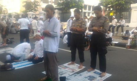 Dua polisi dan satu pengunjuk rasa melakukan Shalat Ashar berjamaah.