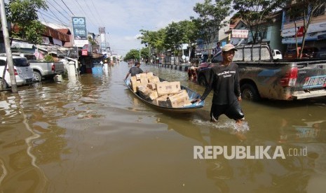 Dua pria menarik perahu saat banjir di Samarinda, Kalimantan Timur.