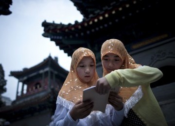 Dua remaja putri membaca Alquran di kompleks Masjid Niujie, Beijing, sembari menunggu waktu berbuka puasa.