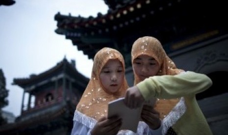 Dua remaja putri membaca Alquran di kompleks Masjid Niujie, Beijing, sembari menunggu waktu berbuka puasa.