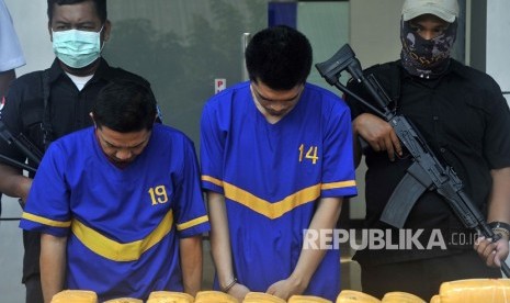 Dua tersangka sindikat narkoba FN (kiri) dan IG (kedua kiri) dijaga aparat BNN Banten saat acara pemusnahan 150 kilogram ganja di halaman Gedung BNN Banten, di Serang, Rabu (31/7/2019).