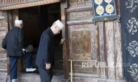 Dua umat muslim masuk ke dalam masjid saat akan menjalankan ibadah salat di Mesjid Agung, di kawasan komunitas muslim di Xi'an, Cina, Sabtu (29/9). 