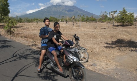 Dua warga di jalan Desa Datah yang berjarak sekitar 10 kilometer dari Gunung Agung yang berstatus awas di Karangasem, Bali, Selasa (26/9).