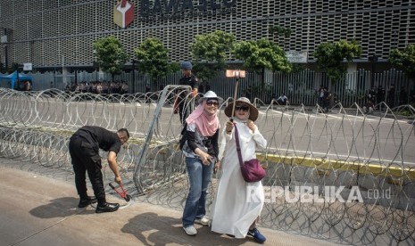 Dua warga melakukan swafoto saat personel korps Brimob memasang kawat berduri di kawasan Kantor Bawaslu, Jakarta, Selasa (21/5/2019). 