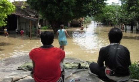 Dua warga menunggu surutnya air luapan Bengawan Solo 