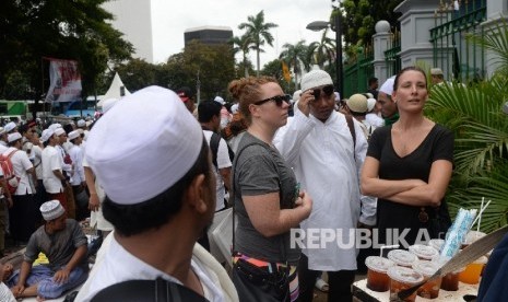 Dua wisatawan asing menonton Aksi Super Damai Bela Islam III di Monumen Nasional, Jakarta, Jumat (2/12).