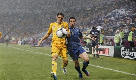 Duel antara Samir Nasri dan pemain Ukraina Taras Mikhalik di tengah hujan deras yang mengguyur stadion Donbass Arena