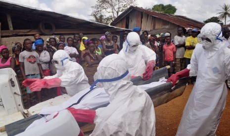 Ebola health care workers carry the body of a man suspected of dying from the Ebola virus in a small village Gbah on the outskirts of Monrovia, Liberia, Friday, Dec. 5, 2014.