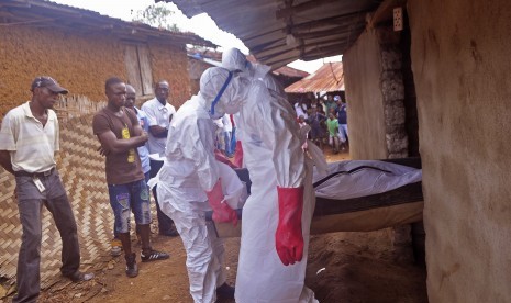 Ebola health care workers carry the body of a man suspected of dying from the Ebola virus in a small village Gbah on the outskirts of Monrovia, Liberia, Friday, Dec. 5, 2014.