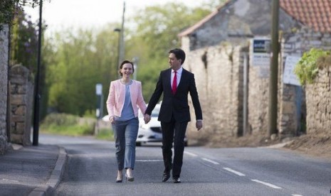 Ed Milliband bersama istrinya Justine berjalan menuju tempat pemungutan suara di Sutton Village Hall di Doncaster, Kamis (7/5).