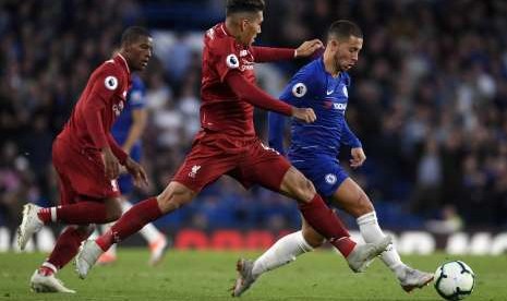 Eden Hazard (kanan) menggiring bola ketika hendak diadang oleh Roberto Firmino (tengah) dan Georginio Wijnaldum (kiri). 