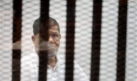 Egypt's ousted Islamist President Mohammed Morsi stands in a defendant cage in the Police Academy courthouse during a court hearing in Cairo, Egypt, Monday, Sept. 15, 2014. 