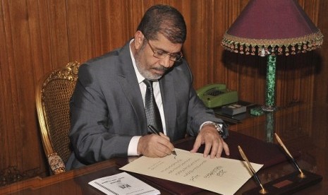 Egypt's President Mohamed Mursi signs a decree to put into effect the new constitution in Cairo December 25,   