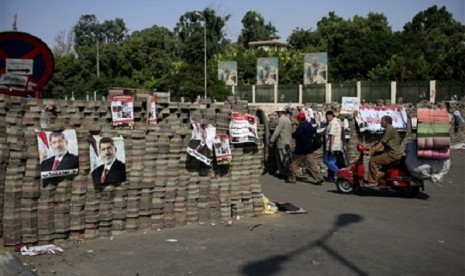 Egyptians walk between brick barricades erected along a street that leads to Rabaah al-Adawiya mosque. The supporters of Egypt's ousted President Mohammed Mursi have installed a camp and hold daily rallies at Nasr City, in Cairo, Egypt, Monday, July 29, 20