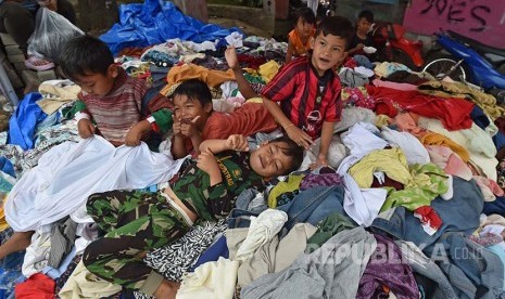 ejumlah anak korban banjir bandan sungai Cimanuk bermain di atas baju yang sumbangan di Cimacan, arogong, Kabupaten Garut, Jawa Barat, Jumat (23/9). Berbagai bantuan berupa makanan, pakaian dan kebutuhan untuk anak terus disalurkan ke posko darurat.