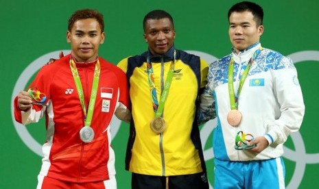 Eko Yuli Irawan (kiri) memegang medali perak yang diraihnya dari cabang angkat besi nomor 62 kg putra.