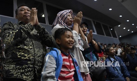 Ekspresi terpidana kasus pelanggaran Undang-Undang Transaksi dan Informasi Elektronik (UU ITE), Baiq Nuril Maknun (tengah) didampingi kerabat saat pengesahan amnesti untuk dirinya pada rapat paripurna DPR di Kompleks Parlemen Senayan, Jakarta, Kamis (25/7/2019). 