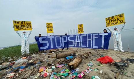 Empat aktivis pemerhati lingkungan berdiri di depan tumpukan sampah plastik di Pulau G di pantai utara Jakarta, Juni 2022. 