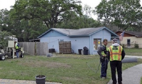 Engineers talk in front of a home where a sinkhole opened up underneath a bedroom late Thursday evening and swallowed a man in Seffner, Florida, US, on Saturday. 