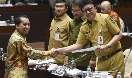 Menteri Dalam Negeri Tjahjo Kumolo (kanan) disaksikan Menteri Komunikasi dan Informatika Rudiantara (kiri) menerima pandangan mini fraksi dari anggota Komisi II fraksi PKS Sutriyono (kiri) saat rapat kerja dengan Komisi II DPR di Kompleks Parlemen, Senayan, Jakarta, Senin (23/10). Pada hari ini, DPR menggelar Sidang Paripurna pengambilan keputusan Perppu Ormas.