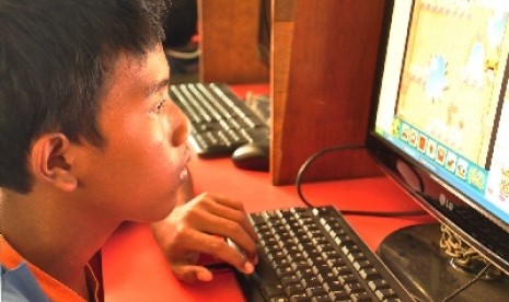 Seorang anak bermain game online di warnet