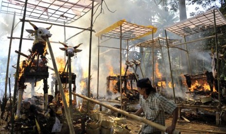 eorang warga menyulutkan api ke peti jenazah berbentuk sapi dalam upacara Ngaben masal di Desa Blahbatuh, Gianyar, Bali, Kamis (8/9). Sebanyak 21 jenazah dan kerangka manusia dikremasi secara bersama-sama dalam ritual 3 tahunan di daerah tersebut.