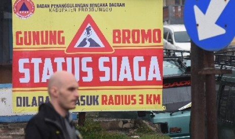 eorang wisatawan mancanegara melintas didepan papan peringatan status siaga Gunung Bromo di Cemoro Lawang, Probolinggo, Jawa Timur, Minggu (6/12). Akibat meningkatnya aktivitas gempa tremornya semakin tinggi, pihak Taman Nasional Bromo Tengger Semeru (TNBT