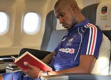 Eric 'Bilal' Abidal sedang membaca Alquran di dalam pesawat. Bek Barcelona itu dikabarkan bakal menjalani transplantasi hati dalam beberapa pekan ke depan.