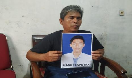 Etes Hidayatullah (54) memegang foto almarhum anaknya, Handi Saputra (18), di kediamannya, Kampung Cijolang, Desa Cijolang, Kecamatan Limbangan, Kabupaten Garut, Senin (27/12). Hendi merupakan salah satu korban penabrakan yang dibuang ke sungai oleh anggota TNI. 