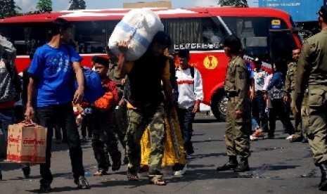 etugas Satpol PP mengarahkan pendatang yang baru tiba untuk diperiksa kelengkapan identitas pribadi pendatang