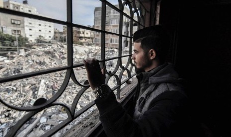 Fadi memandangi puing-puing rumah yang hancur akibat serangan Israel dari rumahnya di Apartemen Al Rahma, Gaza.