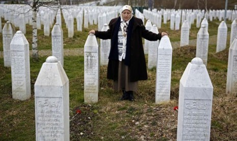 Fadila Efendic meletakkan tangannya di atas pusara putranya dan suaminya di pusat memorial genosida Potocari dekat Srebenica, Bosnia Herzegovina 