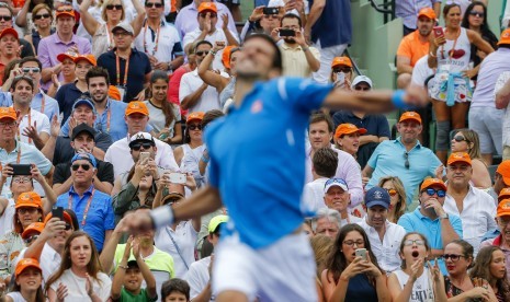 Fan menyaksikan petenis Serbia, Novak Djokovic, melakukan selebrasi usai mengalahkan petenis Jepang, Kei Nishikori, dalam laga final Miami Terbuka di Key Biscayne, Miami, Florida, Amerika Serikat, Sabtu (3/4). 