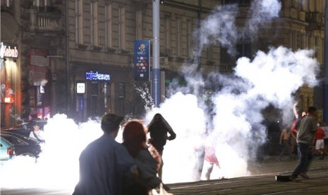 Fans Polandia menyalakan kembang api ketika aparat kepolisian mencoba memisahkan mereka dari perkelahian dengan fans Rusia jelang pertandingan kedua di laga Grup A Piala Eropa 2012 di Warsawa, Polandia, Selasa (12/6). 