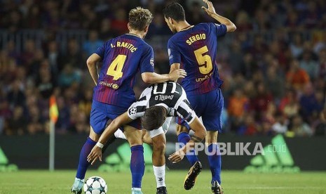 Gelandang FC Barcelona Ivan Rakitic dan Sergio Busquets menahan laju striker  Juventus Paulo Dybala di Stadiun Camp Nou.