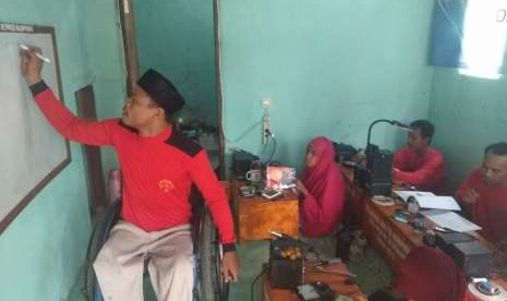 Ferdy Syamsuddin memberikan pelatihan memperbaki telepon genggam ke penyandang disabilitas yang lain.