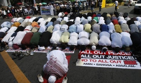 Filipino Muslims hold their Friday prayers near the Presidential Palace as Christians wait for their turn in the background during a 