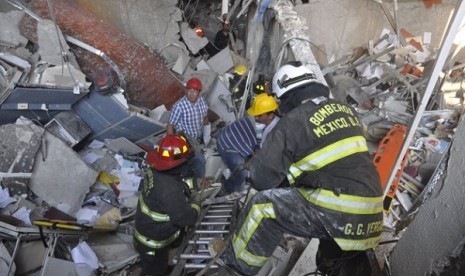 Firefighters belonging to the Tacubaya sector and workers dig for survivors after an explosion at a building adjacent to the executive tower of Mexico's state-owned oil company PEMEX, in Mexico City, Thursday Jan. 31, 2013. 