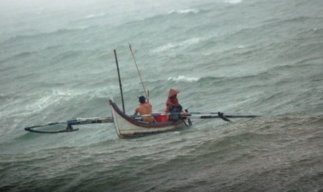 Fishermen works hard to control their small boat during the storm in Padang. (illustration)